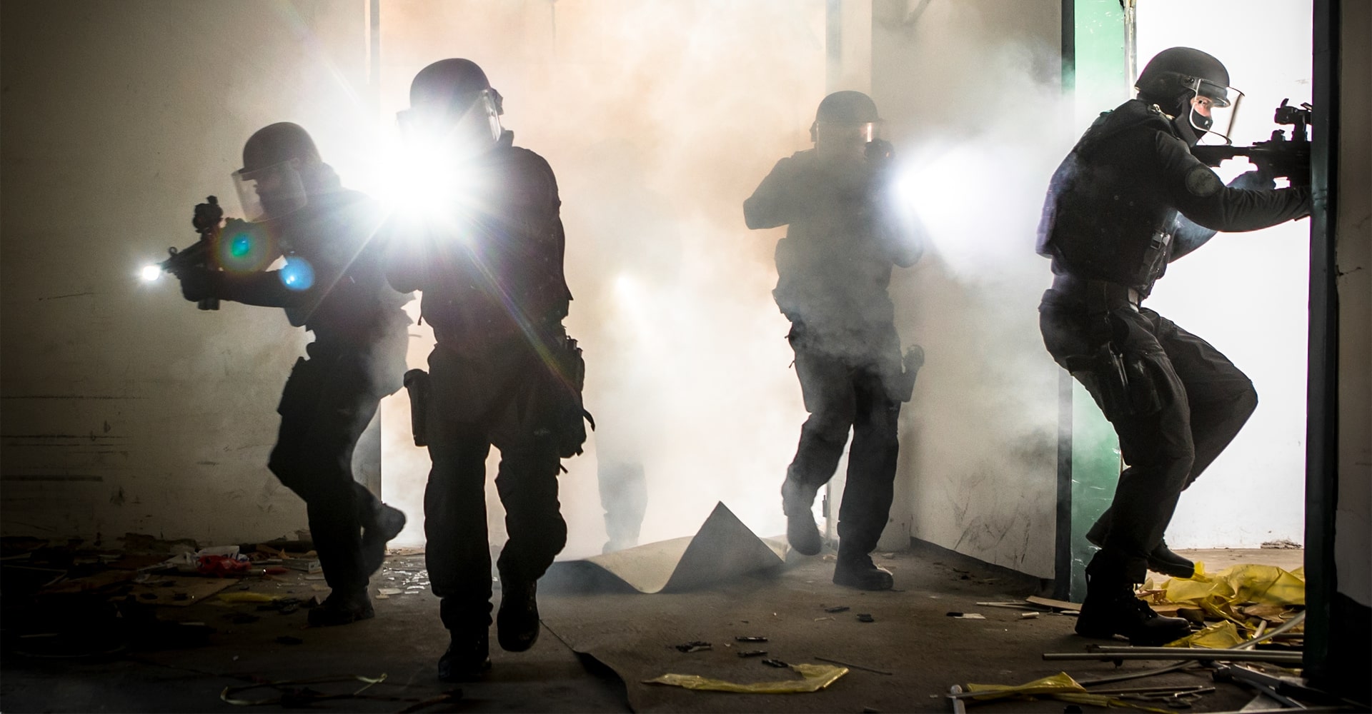 Operators entering a rundown building with debris scattered on the floor.