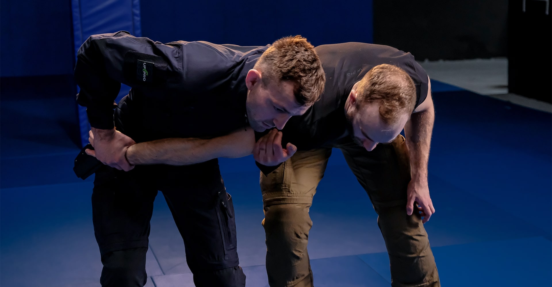 Instructor demonstrating how wrist control, an underhook, head placement, and shoulder pressure work to prevent an attacker from grabbing your gun.