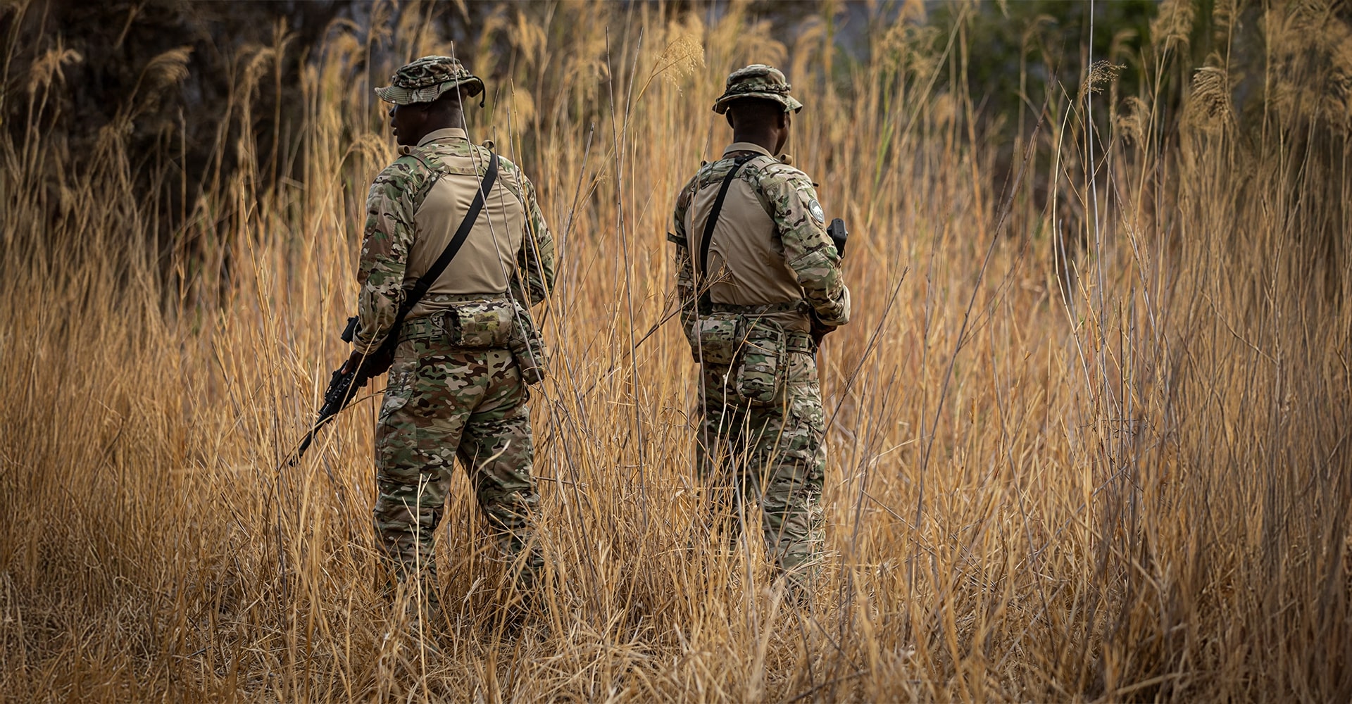 Operators walking through tall grass, showcasing the high-abrasion-resistant materials of their tactical clothing