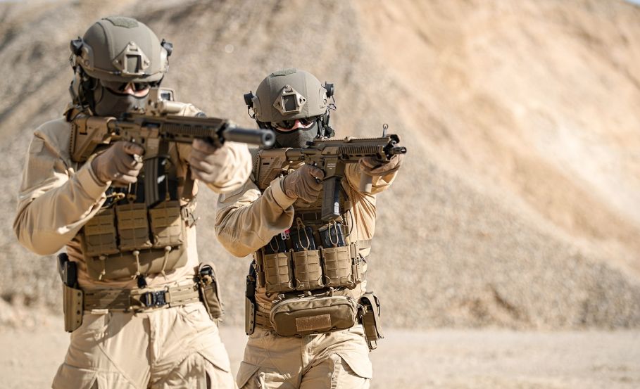 Two operators in a desert environment wearing full tan combat gear, aiming their firearms at a target. What to Look for When Choosing Tactical Hot Weather Gear