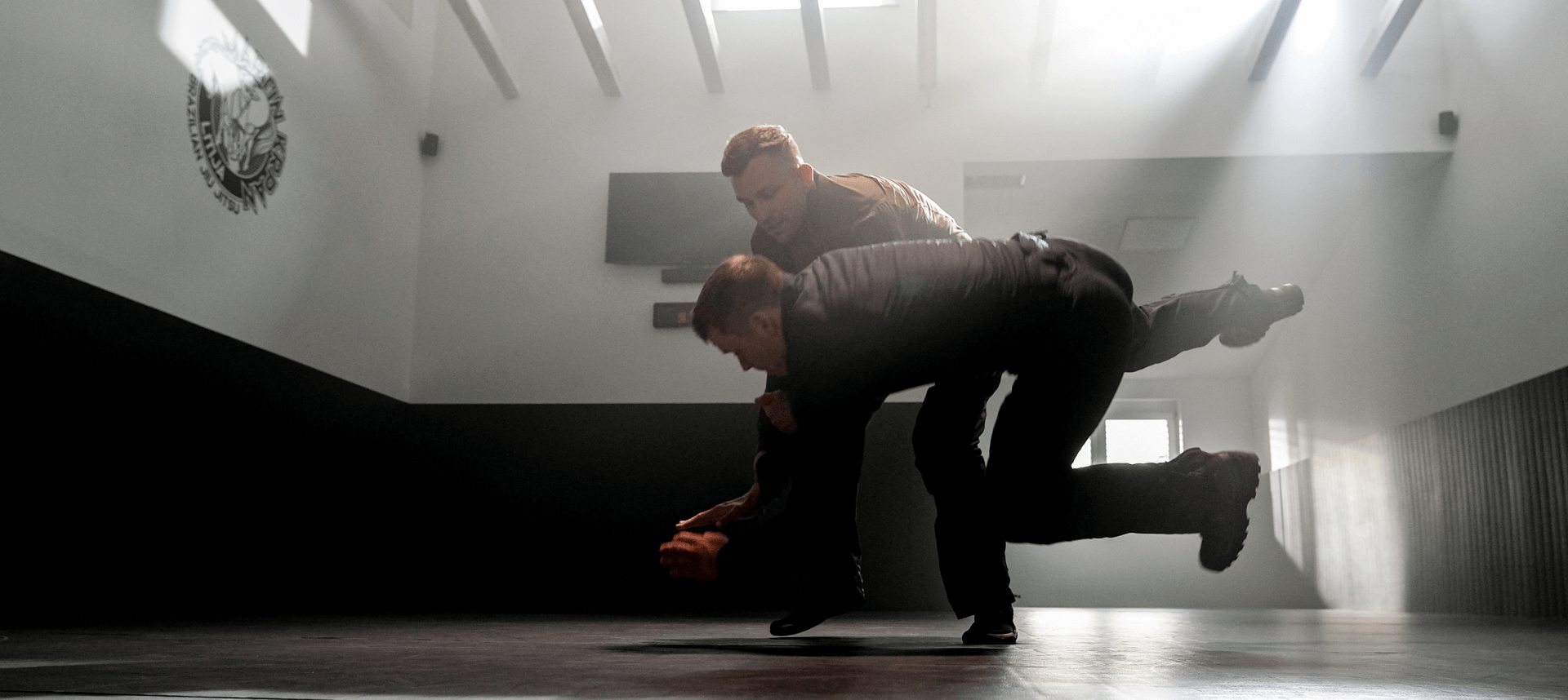 Two men training throw techniques, one throwing the other onto the ground with controlled precision.