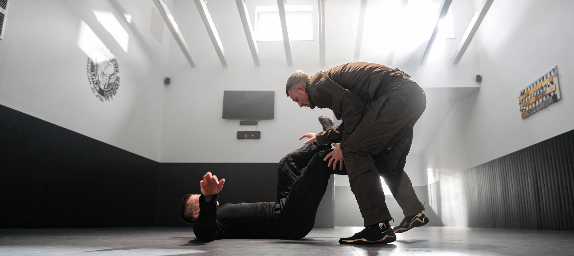 BJJ technique demonstration where one man advances towards a knee-on-belly lock position over his opponent lying on the ground.