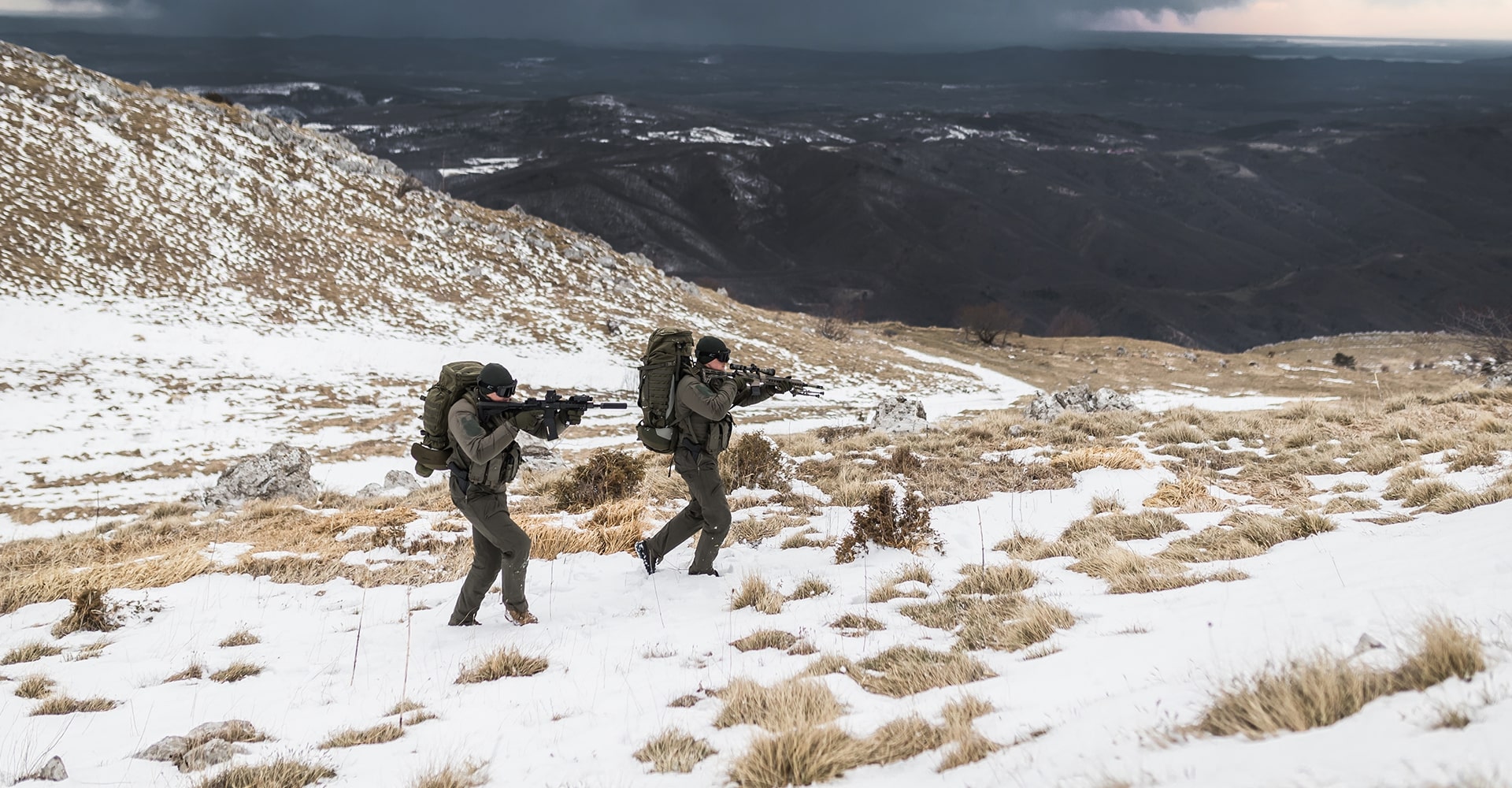 Snow-covered winter landscape with two operators moving through icy winds.