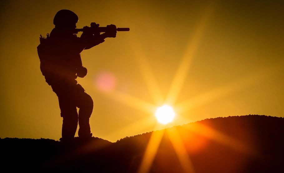 Operator stading on a hill holding a firearm in tactical gear How Heat Affects the Body and the Power of Hot Weather Gear