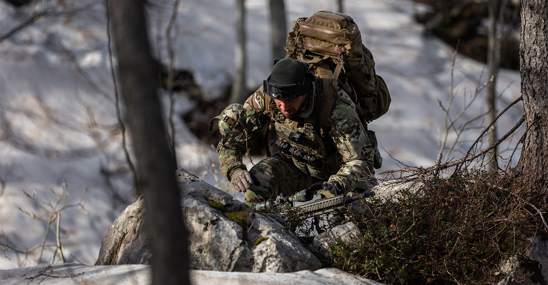 Operator walking on rugged snowy terrain, demonstrating the mobility of winter tactical clothing.