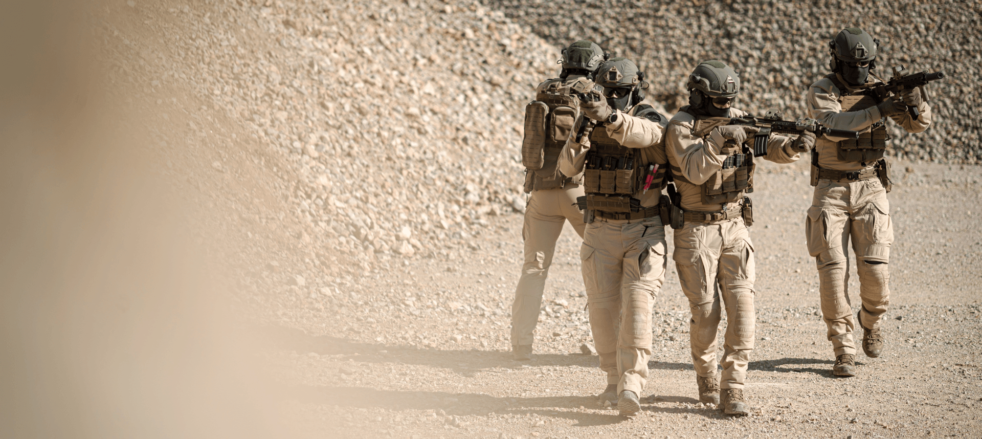 A team of soldiers in desert terrain conducts a perimeter check, scanning the surroundings for any potential threats. 