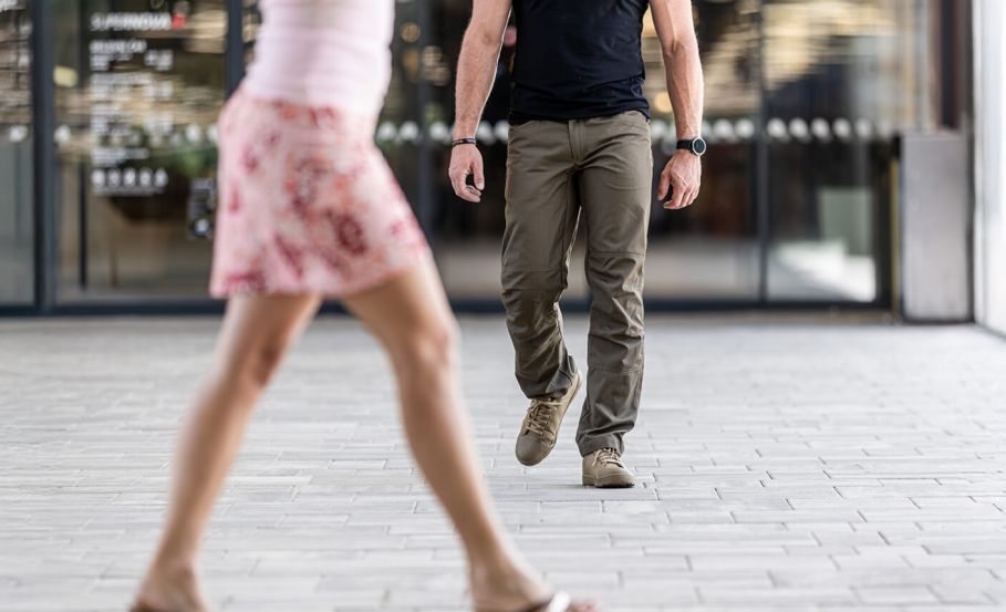 Individual walking confidently in an urban setting while observing his environment, demonstrating situational awareness.