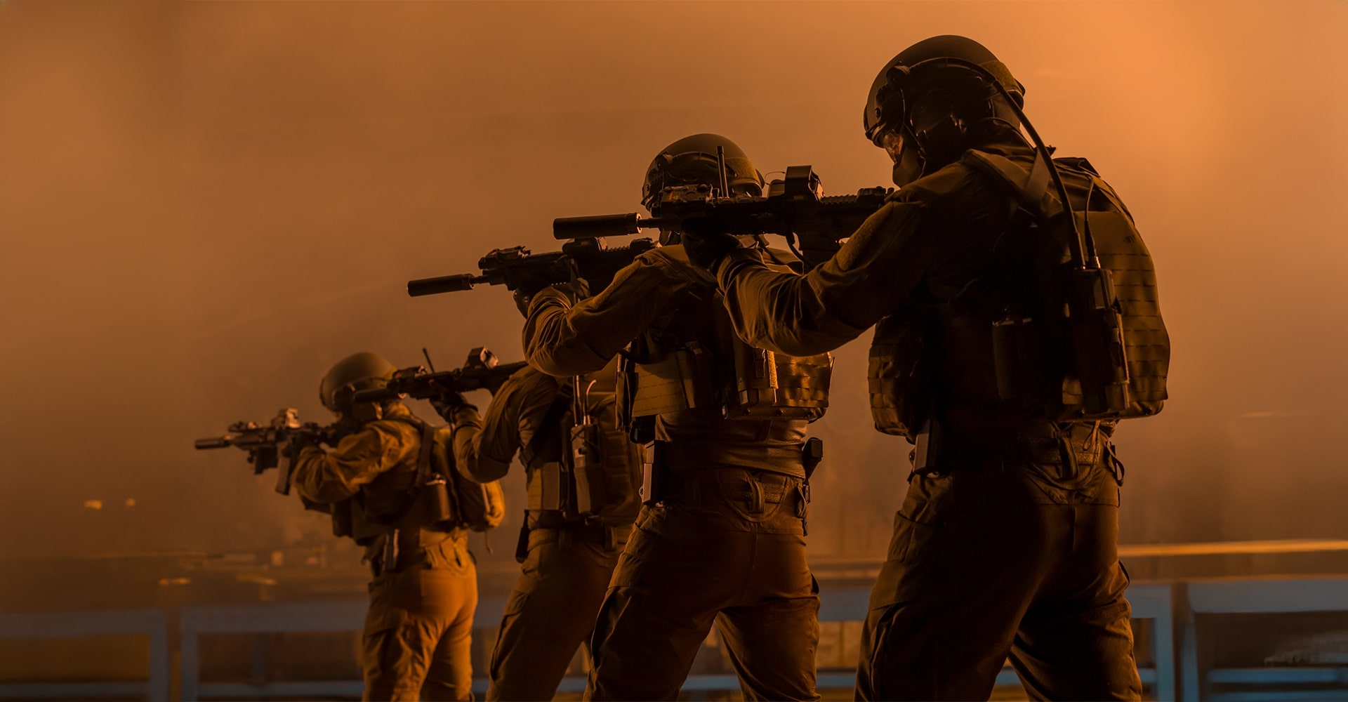 Operators aiming their firearms in formation, surrounded by thick fire and smoke.