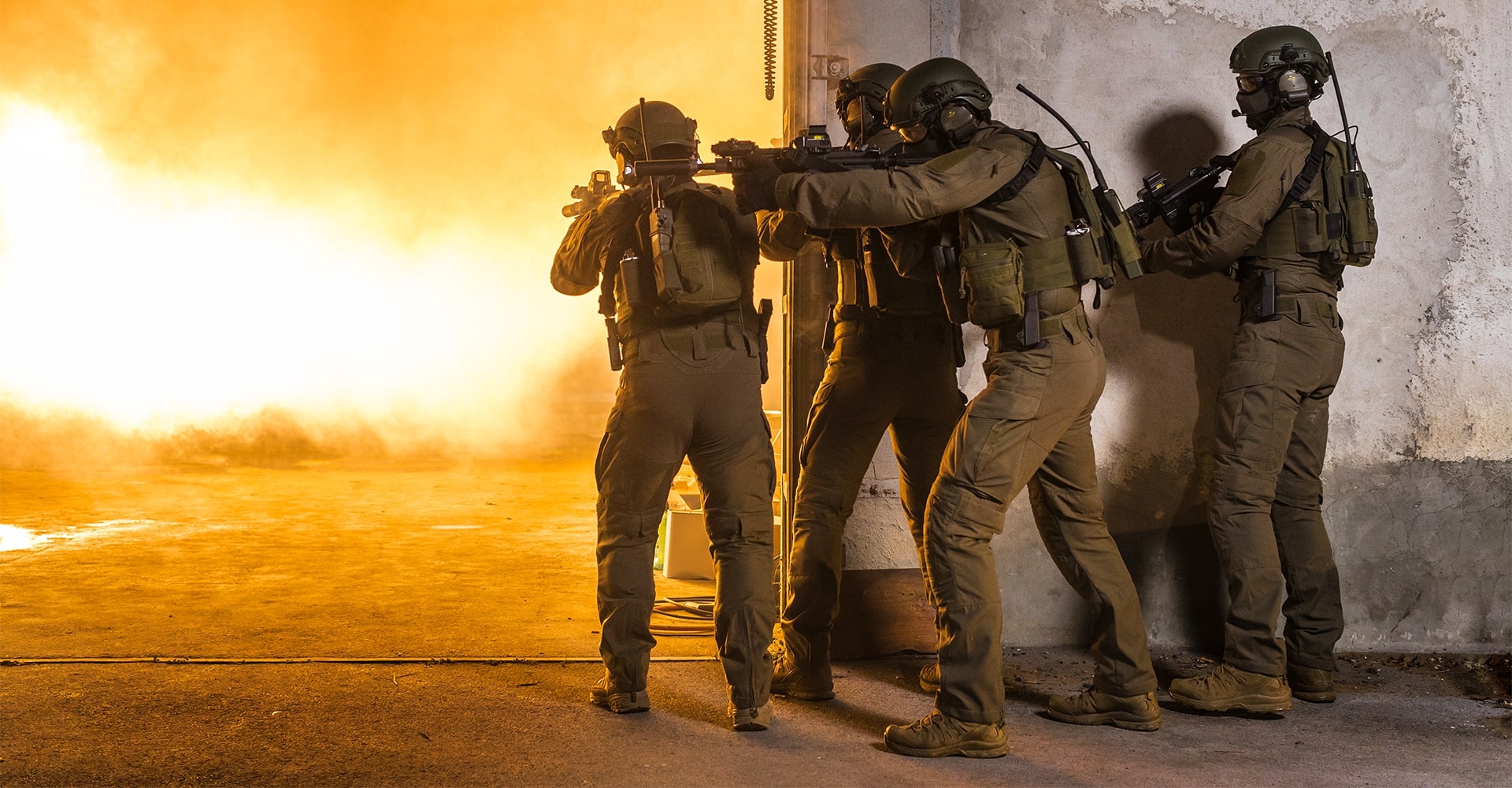 Operators taking cover behind a wall as fire and an explosion erupt on the opposite side.