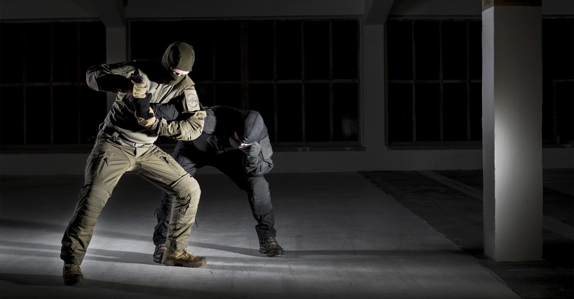 Two operators in a fight scene, one attempting to disarm the other using martial arts techniques.