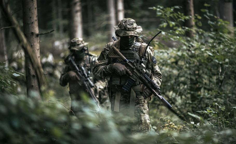 Two operators walking through a lush European forest, wearing full military BDUs. From High and Hot to Cold and Wet: New Areas of Operations for NATO Special Forces