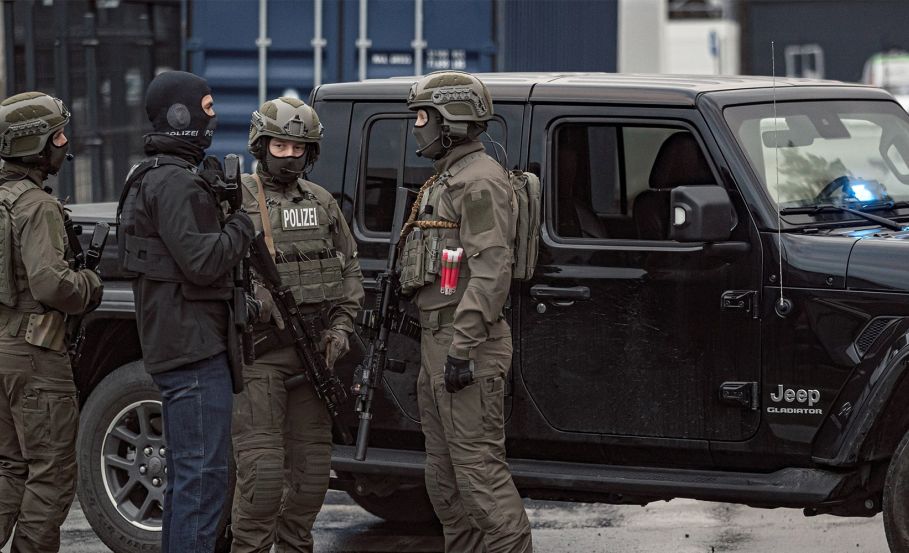 Law enforcement special forces operators standing in a circle in front of a car, preparing for a mission and discussing their plan. Tactical Tracking Across Sectors: Military, Law Enforcement, Indigenous, and Beyond