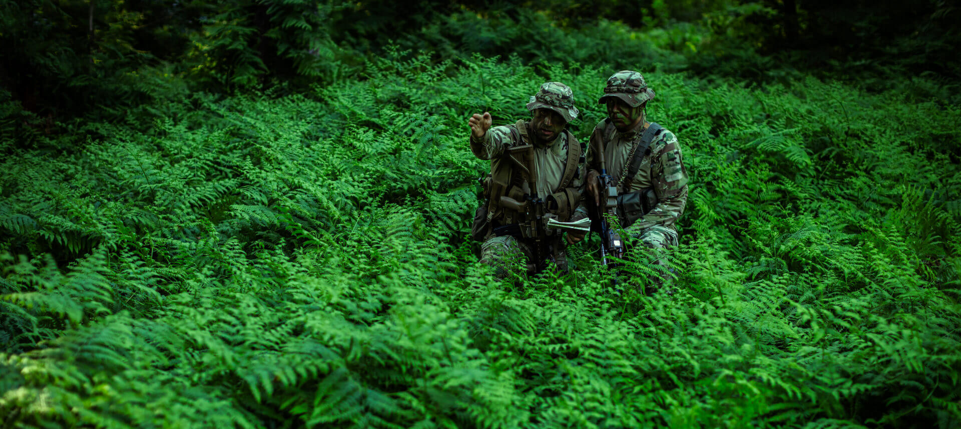 Tactical operators using jungle-specific camouflage patterns to blend seamlessly into their environment.