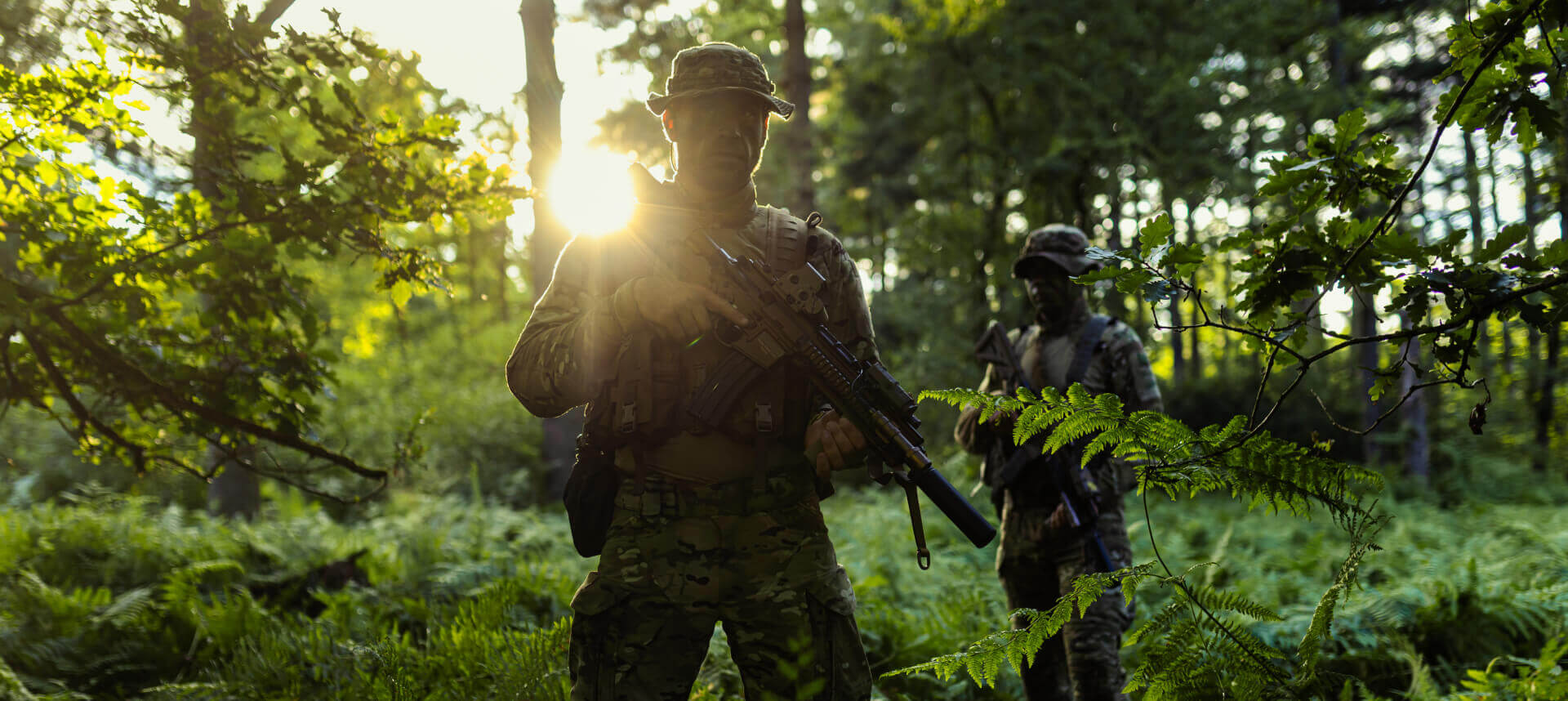 A soldier in a sunlit forest, highlighting the adaptability of tropical camouflage to bright, mixed-light conditions.