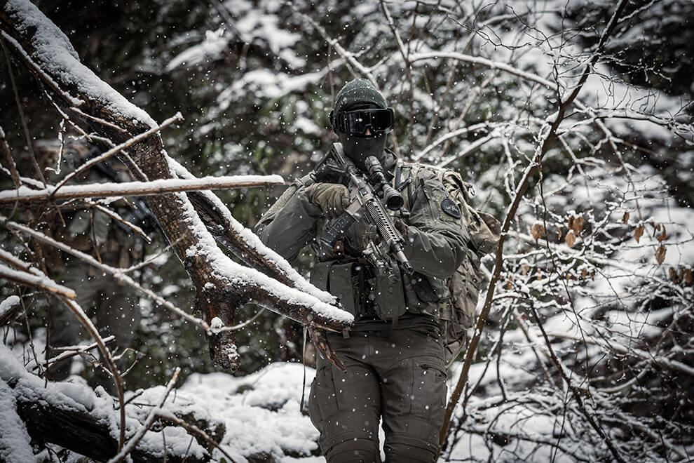 Tactical operator walking through a snowy forest