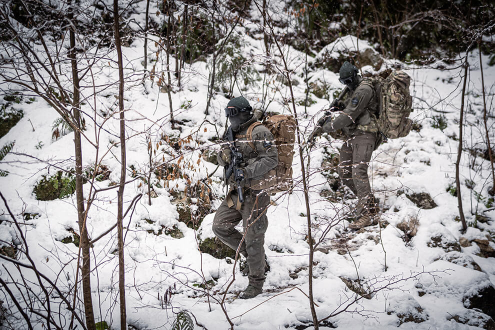 Two tactical operators walking through a snowy forest