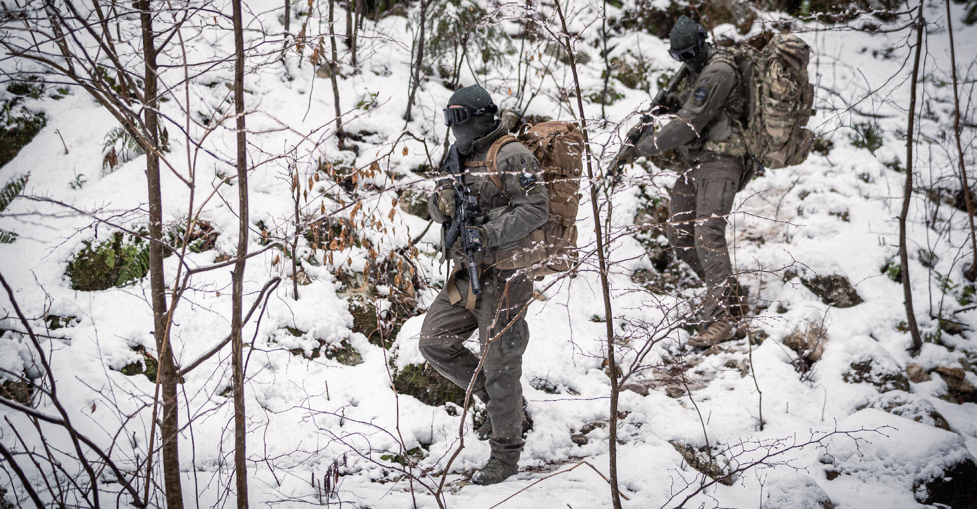 A snowy forest with two operators moving quietly, the crunch of their footsteps on the snow breaking the silence.