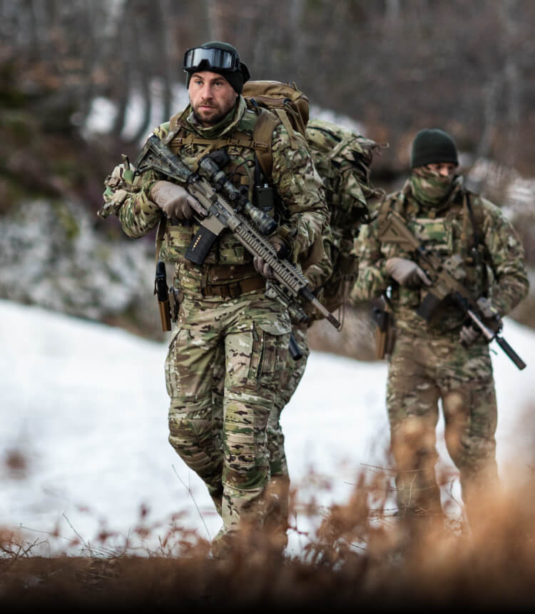 GEARING UP FOR ACTIVITY LEVELS  Alt text: Soldiers in MultiCam winter gear walking uphill in a snowy environment.
