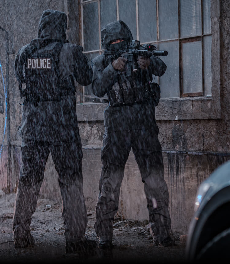 UNDERSTANDING WEATHER EXTREMES Two police officers in rain suits securing a perimeter in a severe downpour in front of an abandoned industrial building.